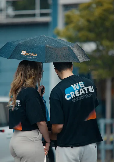 Zwei Teammitglieder von C-Pictures stehen unter einem Regenschirm