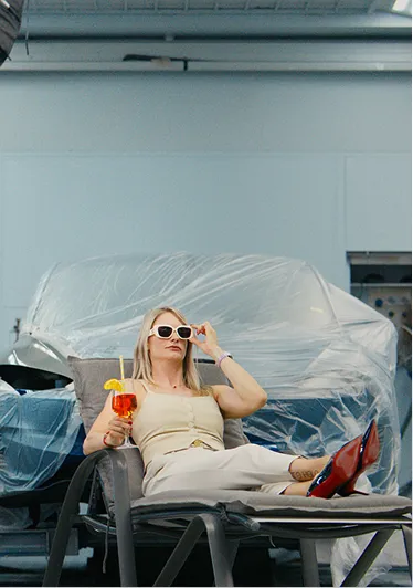 Darstellerin mit Sonnenbrille und Drink auf einer Liege beim Dreh