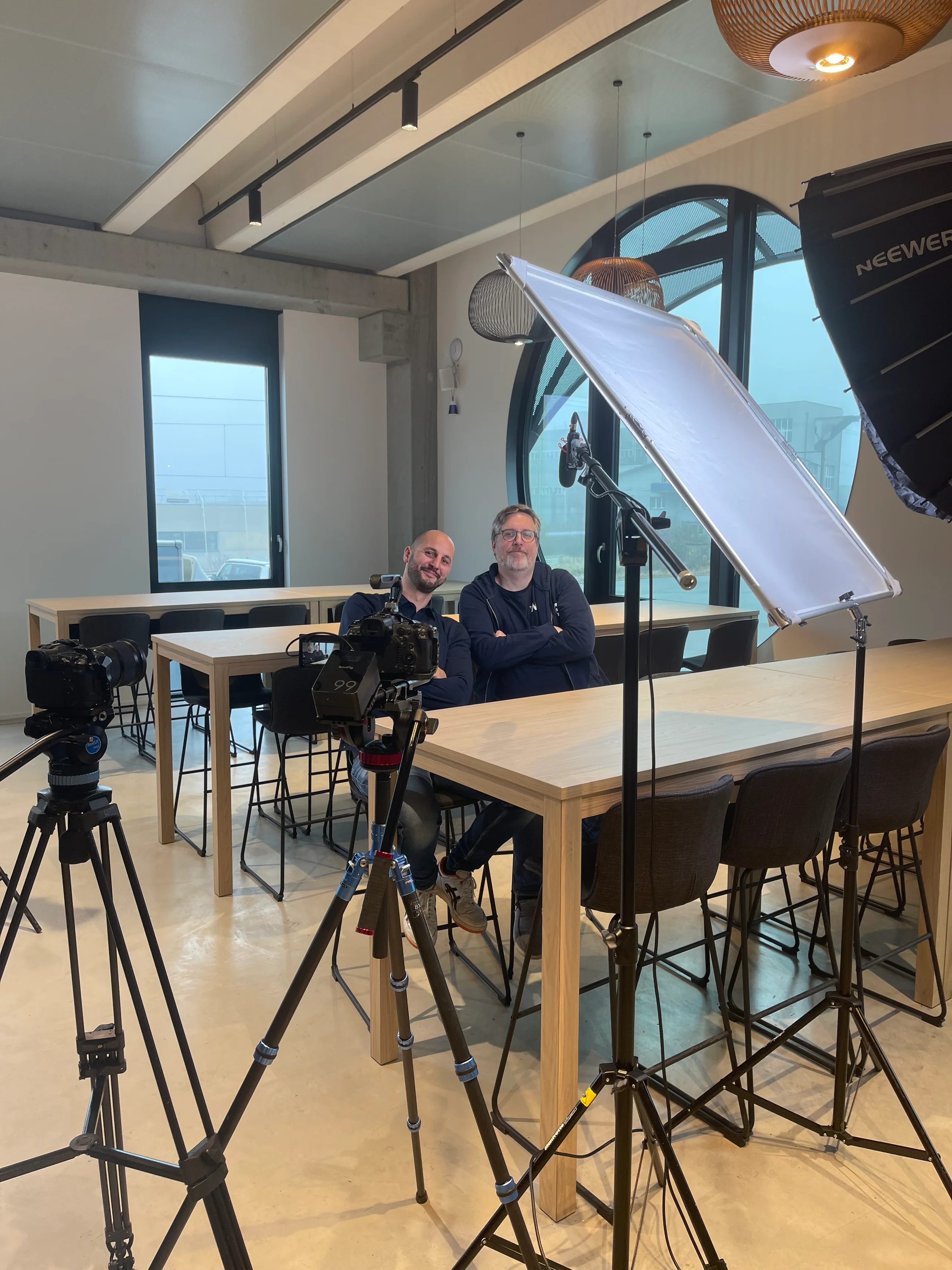 Dreh bei Arvato Systems: Kamera, Stativ und Softbox vor zwei Gesprächspartnern