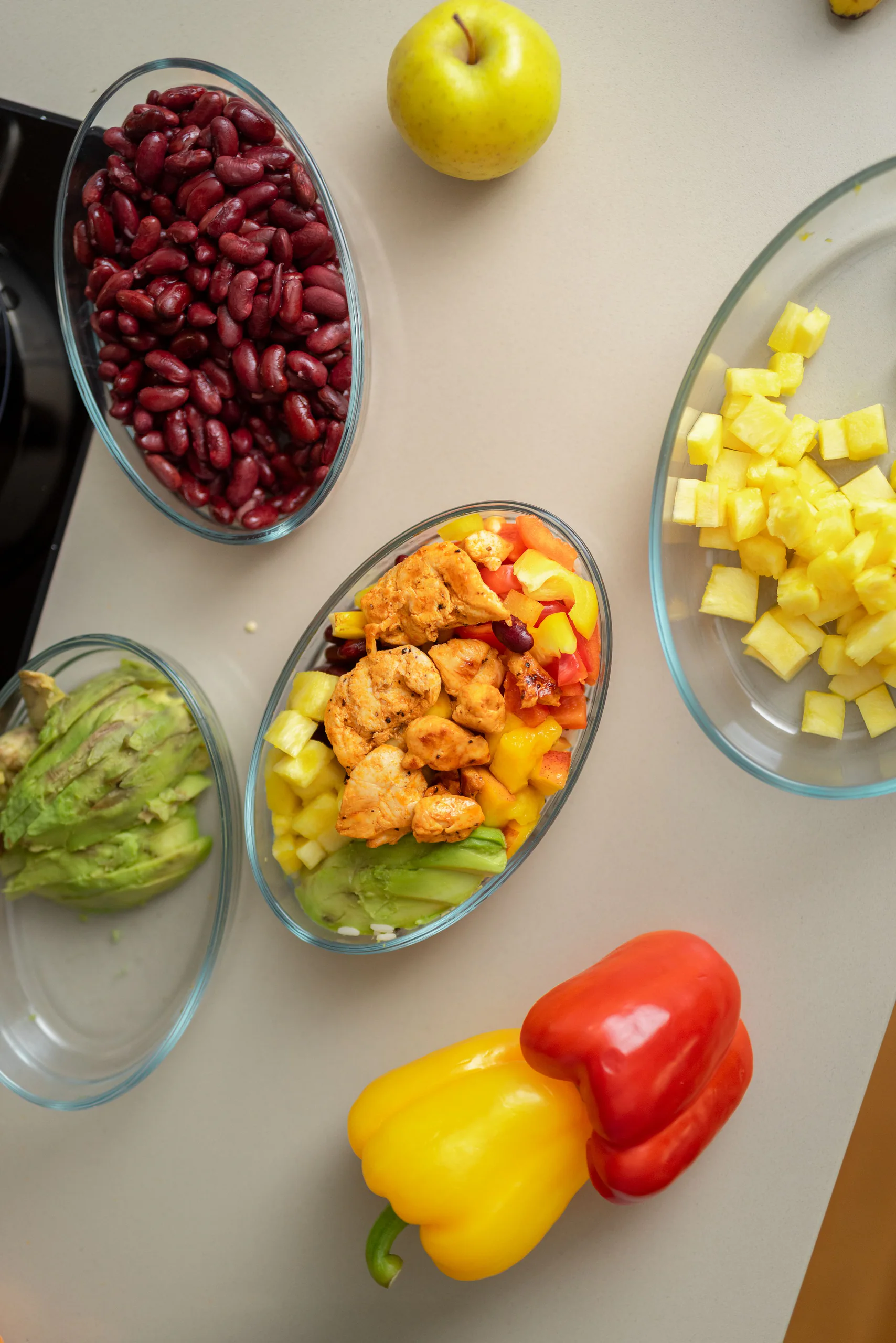 Meal-Prep-Schalen mit Kidneybohnen, Avocado, Ananas und Peperoni von oben