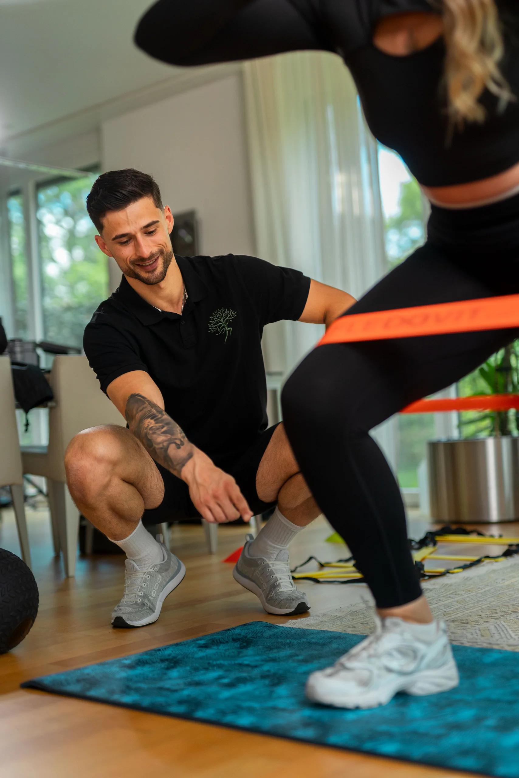 Coach beobachtet eine Kundin beim Training auf der Matte