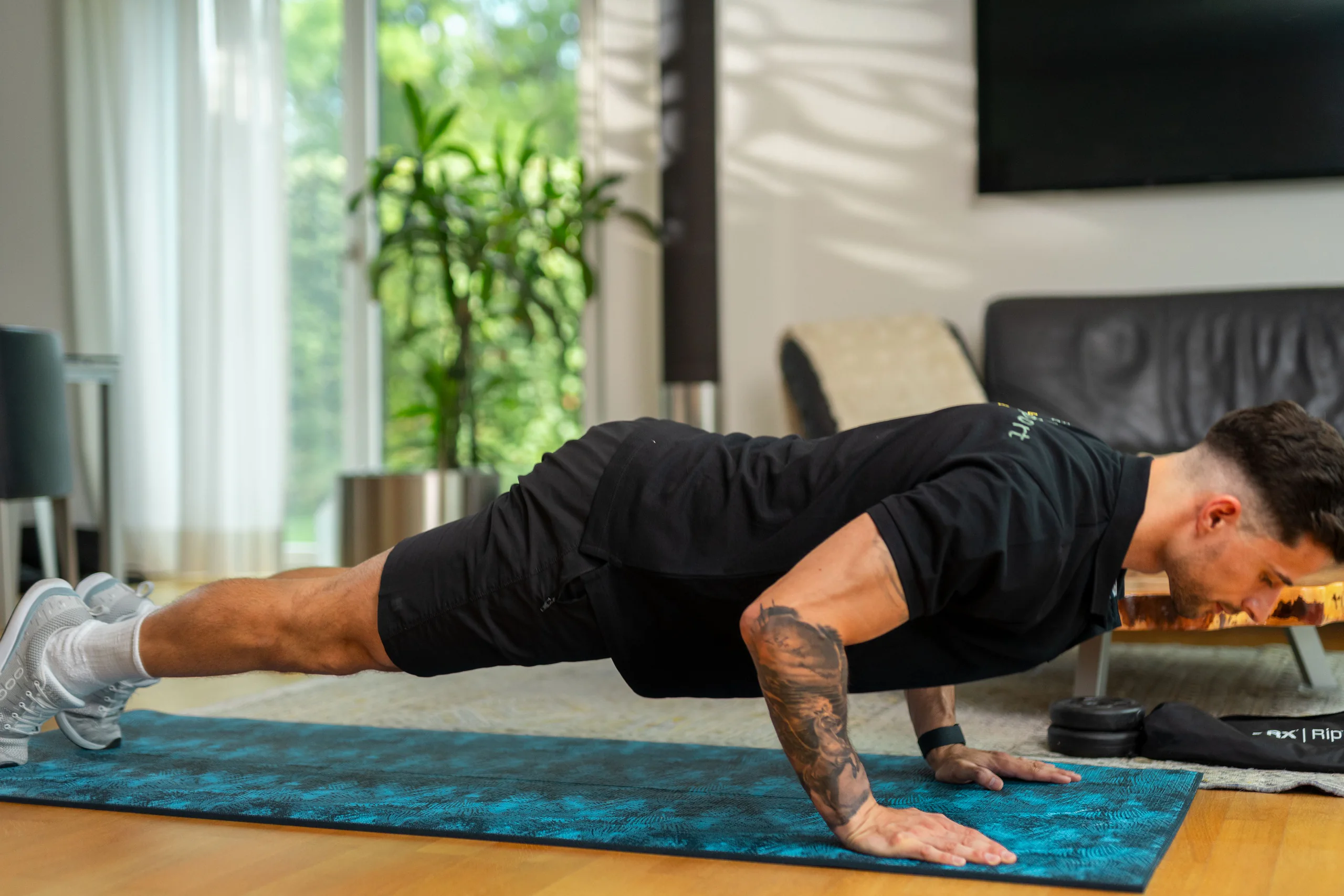 Trainer macht Liegestütze auf einer Matte im Wohnzimmer