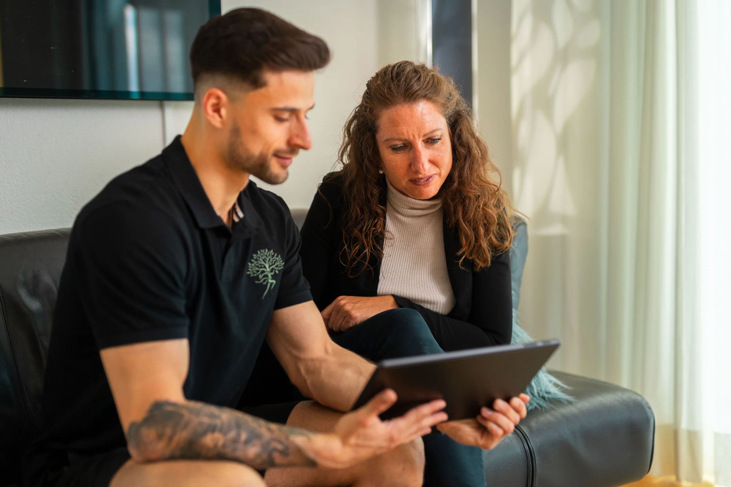 Coach zeigt einer Kundin den Trainingsplan auf dem Tablet