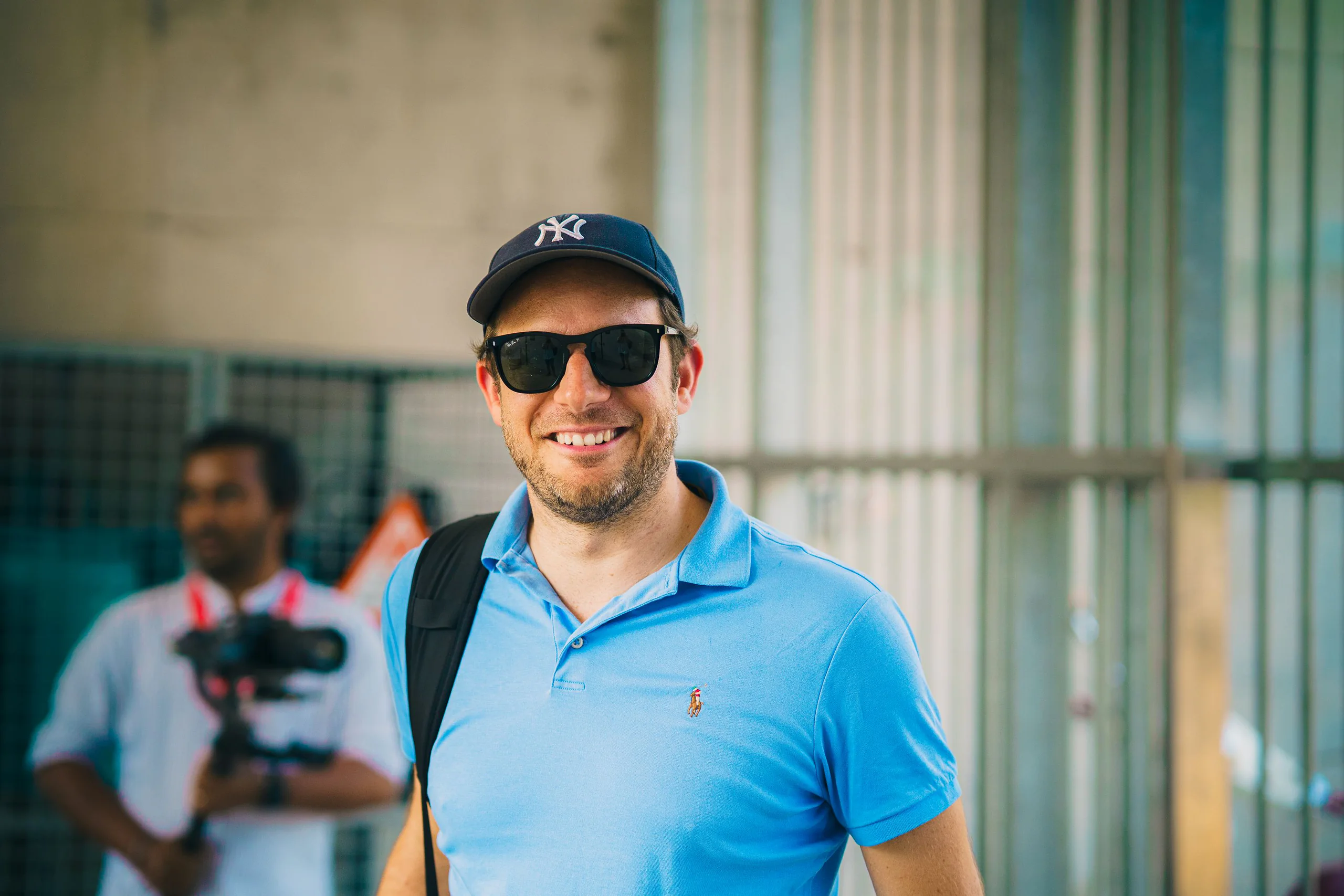 Gast mit Sonnenbrille lacht, im Hintergrund filmt ein Kameramann
