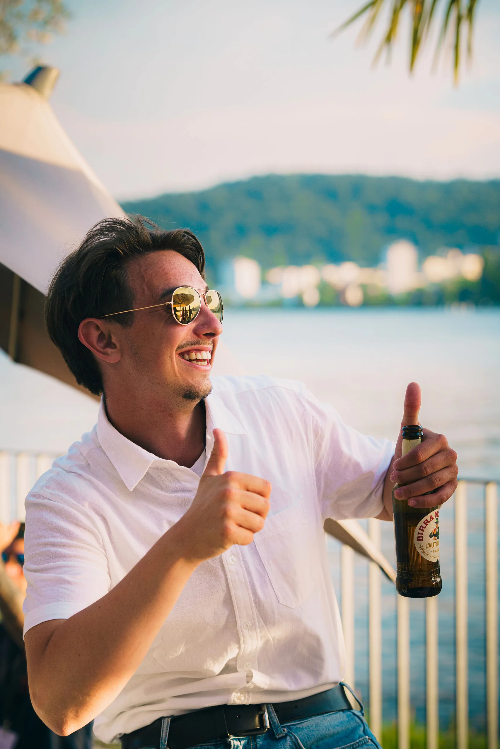 Gast mit Sonnenbrille hält ein Bier und zeigt den Daumen nach oben