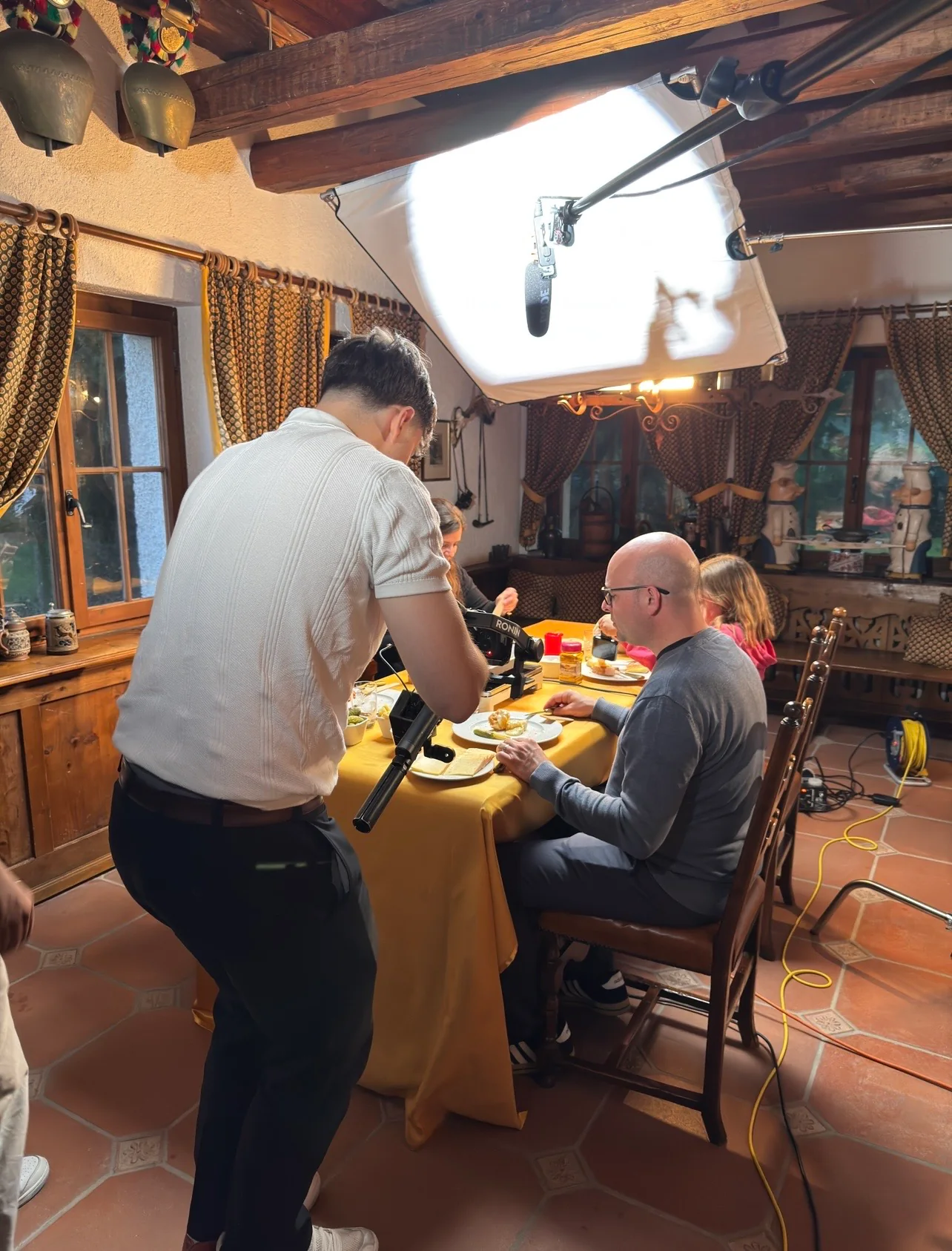 Dreh im Restaurant: Kameramann filmt Gäste am gedeckten Tisch