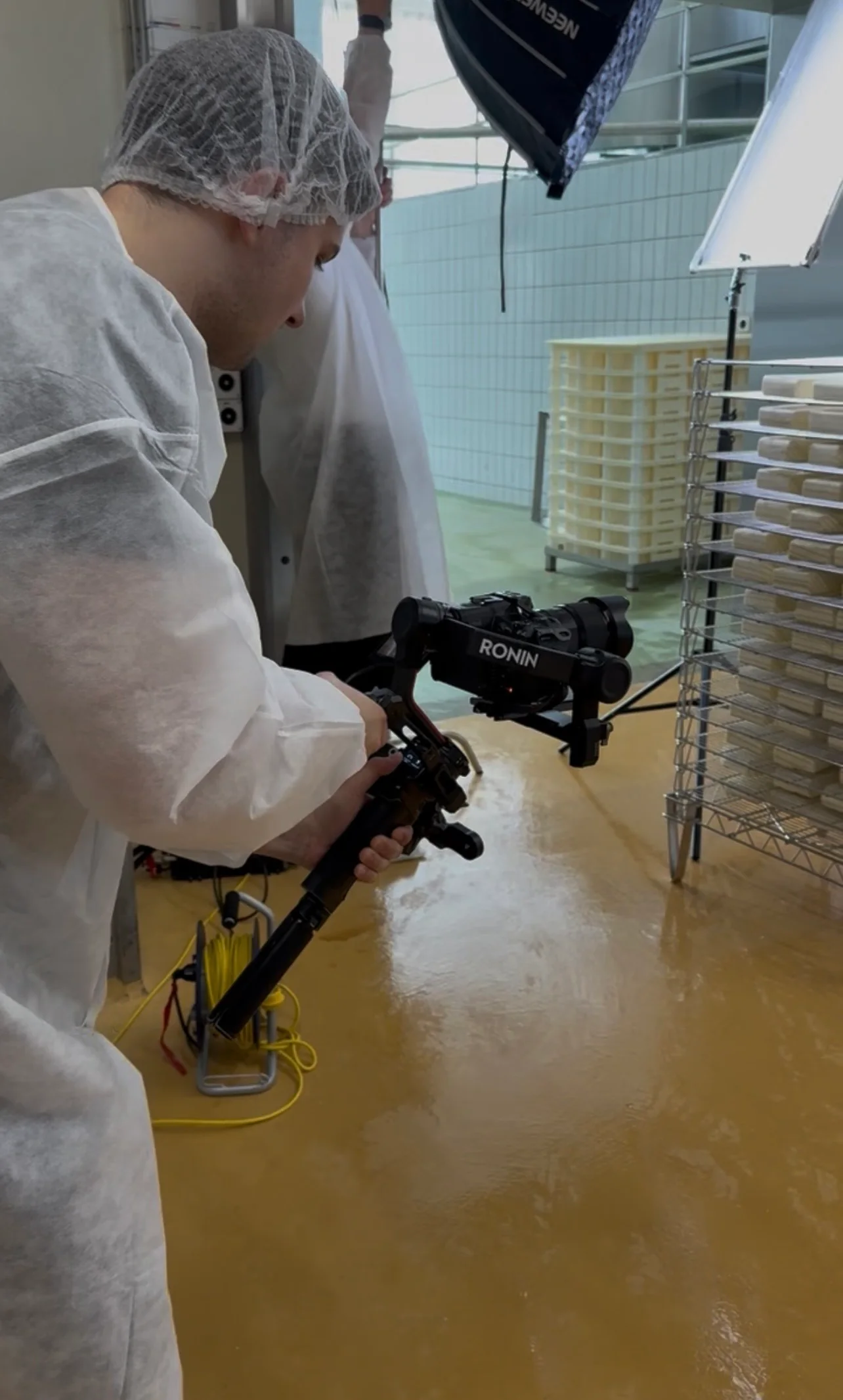 Kameramann in Schutzkleidung und Haarnetz mit Gimbal in der Käserei