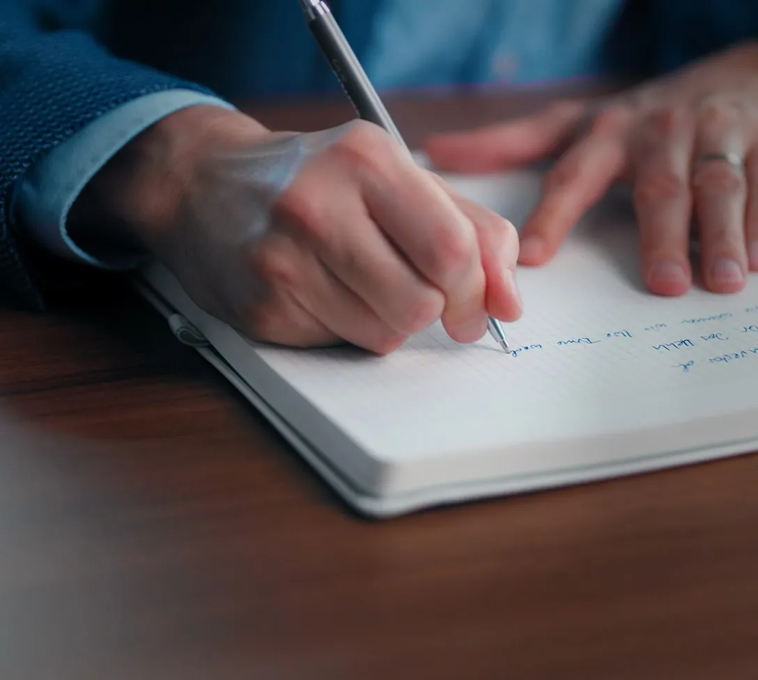 Hand schreibt Notizen in ein Notizbuch bei der Videokonzeption