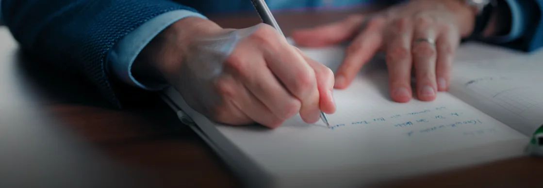 Hand schreibt Notizen in ein Notizbuch bei der Videokonzeption